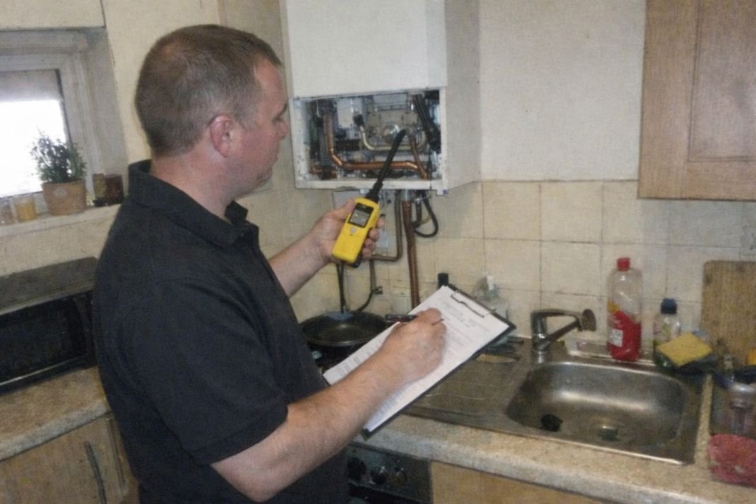 A representative image of an engineer conducting a gas inspection in a small UK rental kitchen.