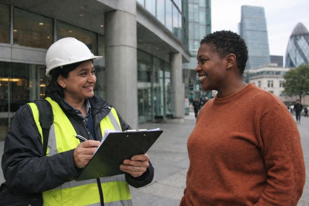 An illustrative image of a EICR inspector speaking with a site representative in front of a modern office building