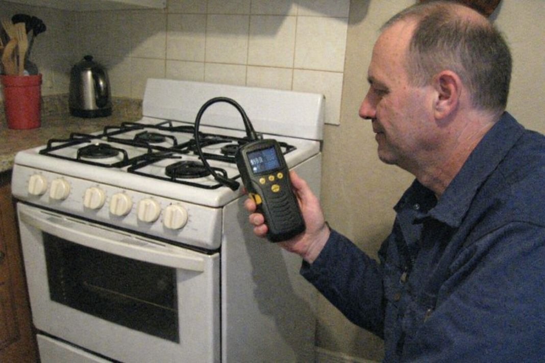 An illustrative image of a gas engineer with a handheld gas detector beside a standalone gas cooker