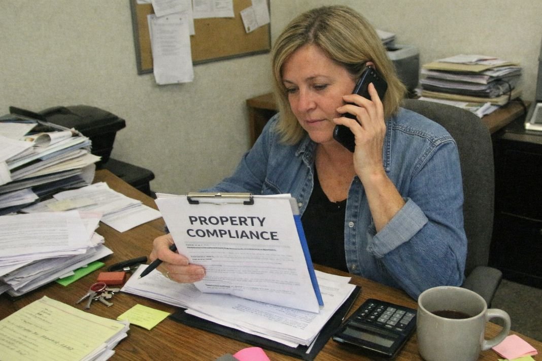 An illustrative image of a property manager speaking on phone reviewing property compliance documents