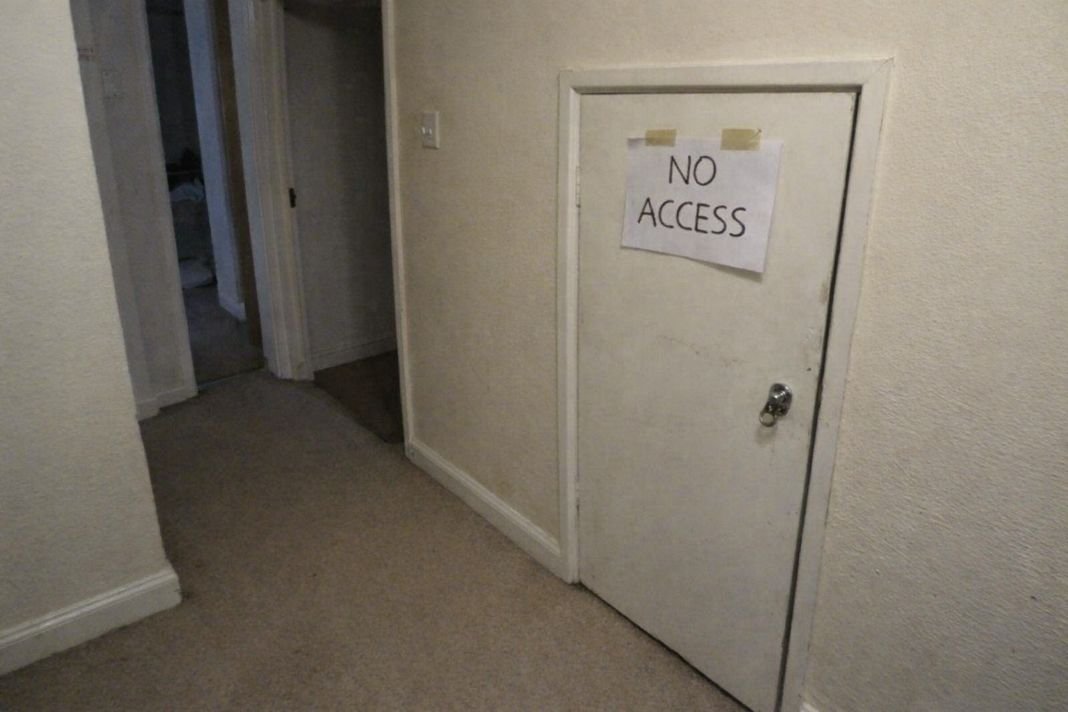An illustrative image of an empty hallway in a rental property with a locked meter cupboard door and no access note