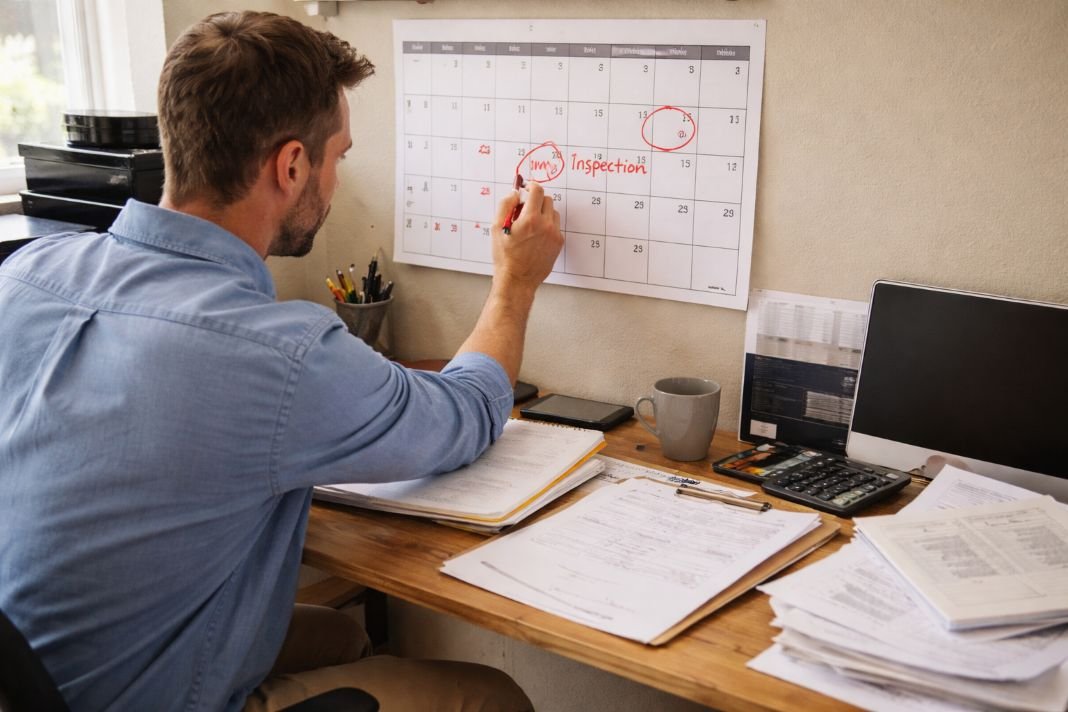 An illustrative photo of a property manager marking inspection dates on a wall calendar
