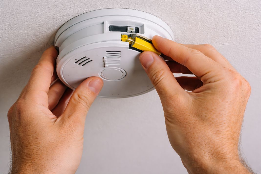 An illustrative image of a battery-powered smoke detector being installed