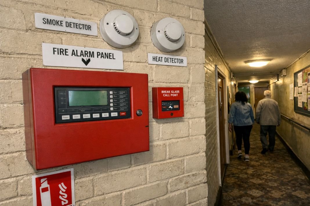 An illustrative image of a red fire alarm panel and several clearly labelled detectors