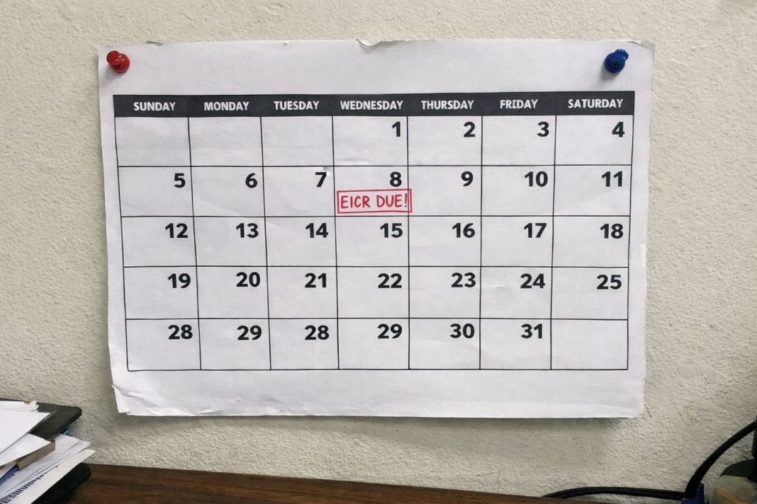 An illustrative image of a calendar pinned to an office wall with EICR due dates marked in red