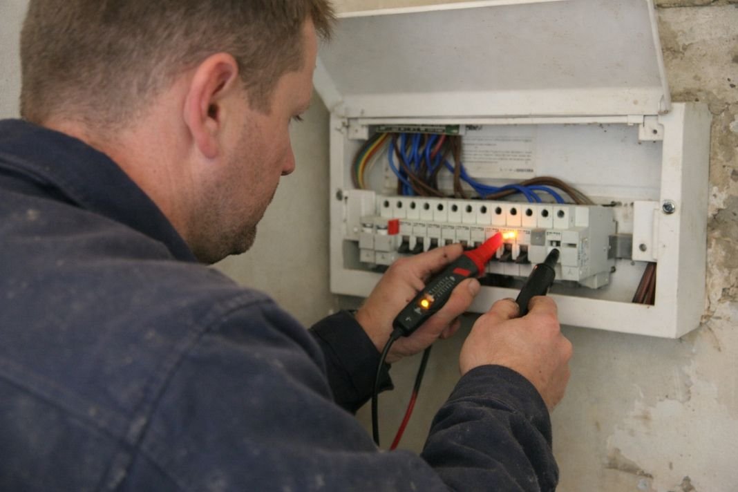 An illustrative image of a domestic electrical consumer unit being checked with a voltage tester